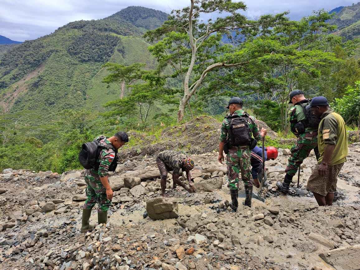 Satgas TNI Bersama Warga memperbaiki jalan yang terputus sebagai penghubung dua kabupaten di pegunungan Papua, kamis 16 Februari 2023